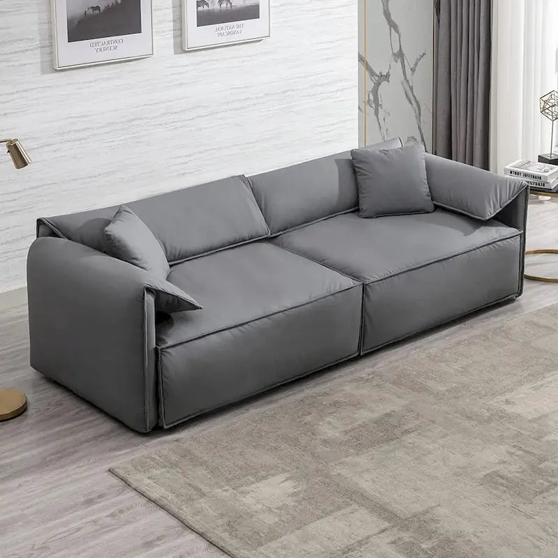 Canapé Mixoy 4 places à assise profonde et rembourrée, style italien minimaliste, 97 cm, avec accoudoirs en forme d'oreilles d'éléphant et coussin décoratif.