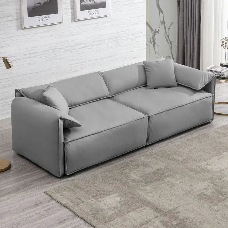 Canapé Mixoy 4 places à assise profonde et rembourrée, style italien minimaliste, 97 cm, avec accoudoirs en forme d'oreilles d'éléphant et coussin décoratif.